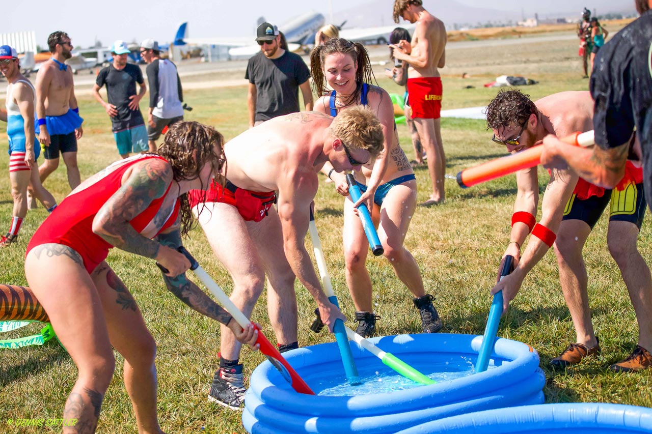 Several people in swimsuits play with water shooters