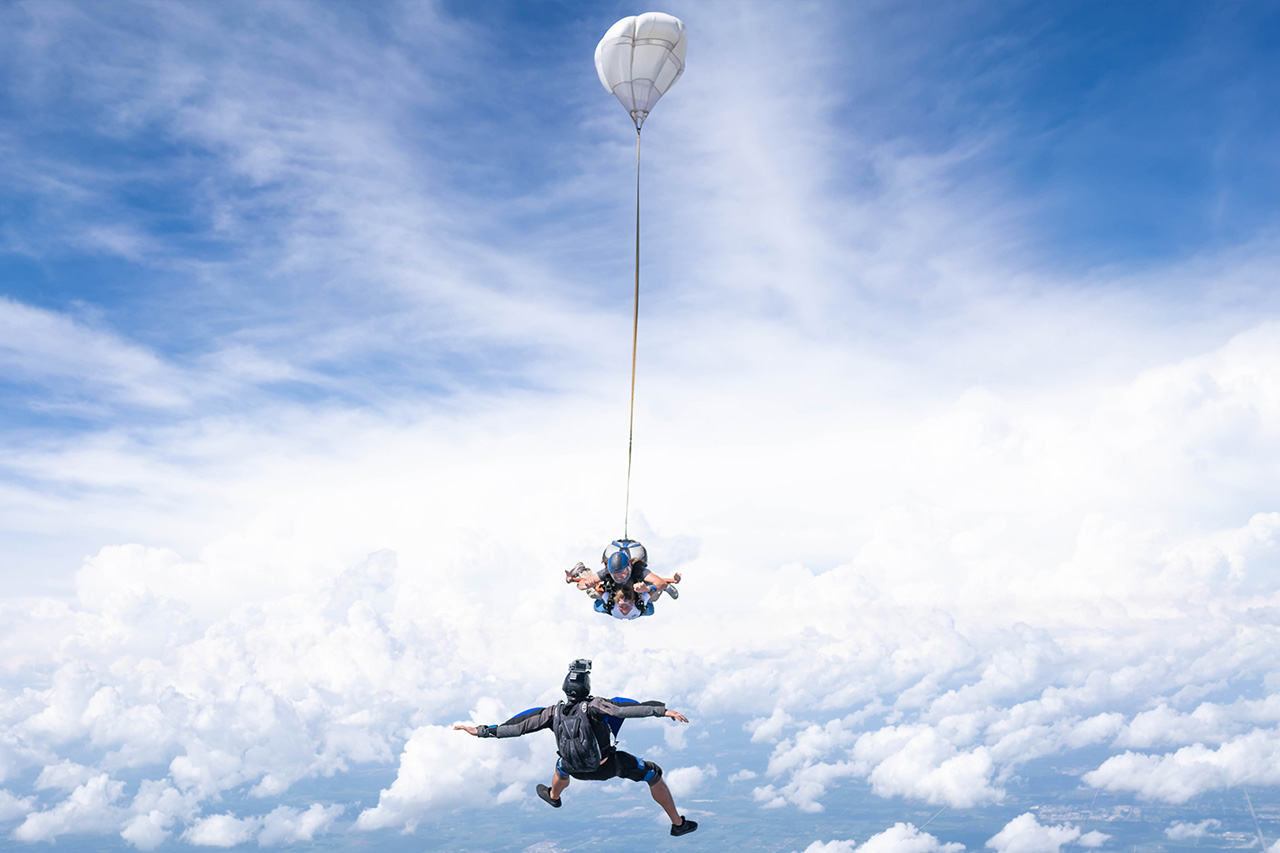 Outside view of a videographer capturing a tandem skydiving student and instructor in freefall
