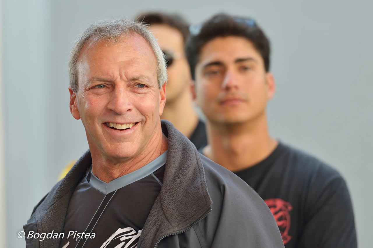 Professional skydiver Dan BC smiles toward the camera with two men standing behind him
