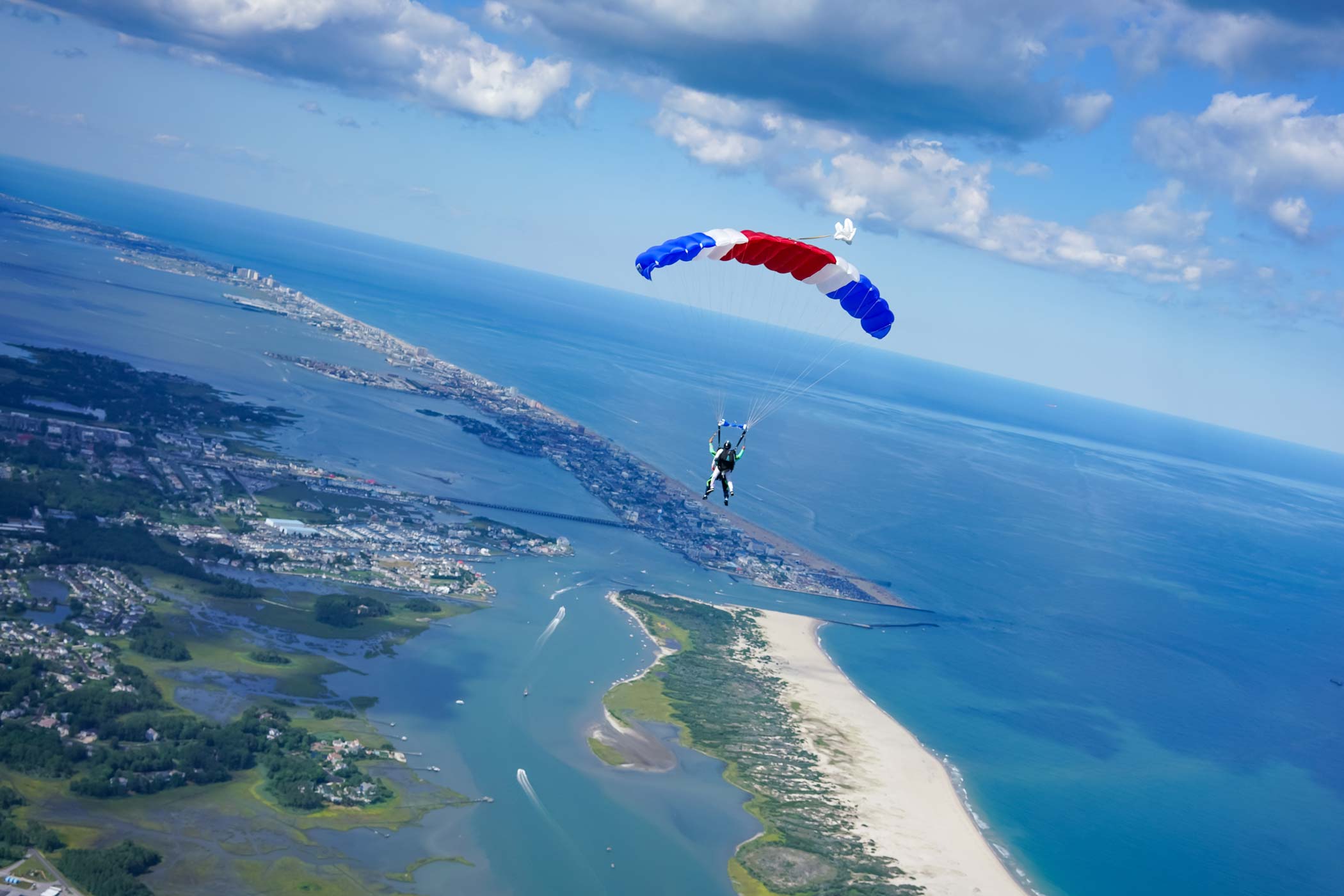 Tandem skydiving student and instructor under canopy flying over a beautiful coastline