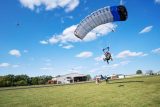 Tandem skydiving student and instructor coming in for landing in a grassy field
