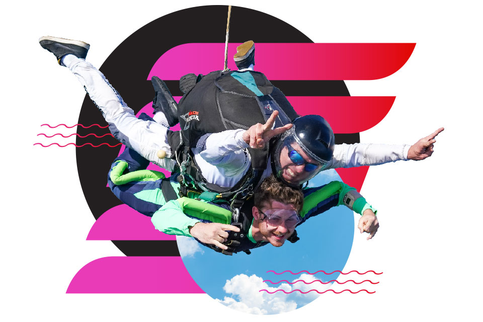 Two people tandem skydiving, both smiling with outstretched arms, one flashing a peace sign. They are in front of a graphic background with pink and black shapes and a small patch of blue sky with clouds.